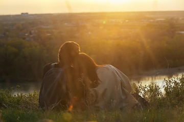 um-casal-apaixonado-abracando-senta-se-em-uma-margem-alta-do-rio-nos-raios-do-sol-do-sol_537579-854