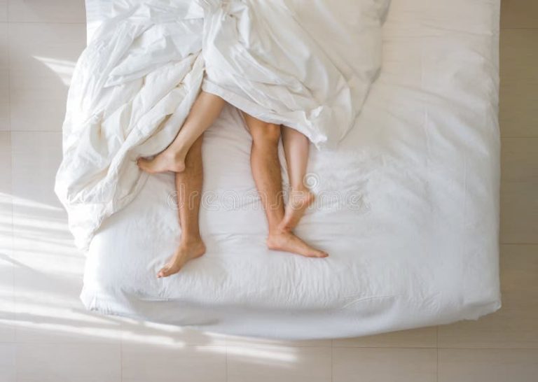 ideia-superior-do-sono-romântico-dos-pares-pés-desencapados-de-seus-que-encontram-se-em-uma-cama-com-cobertura-branca-no-150495308